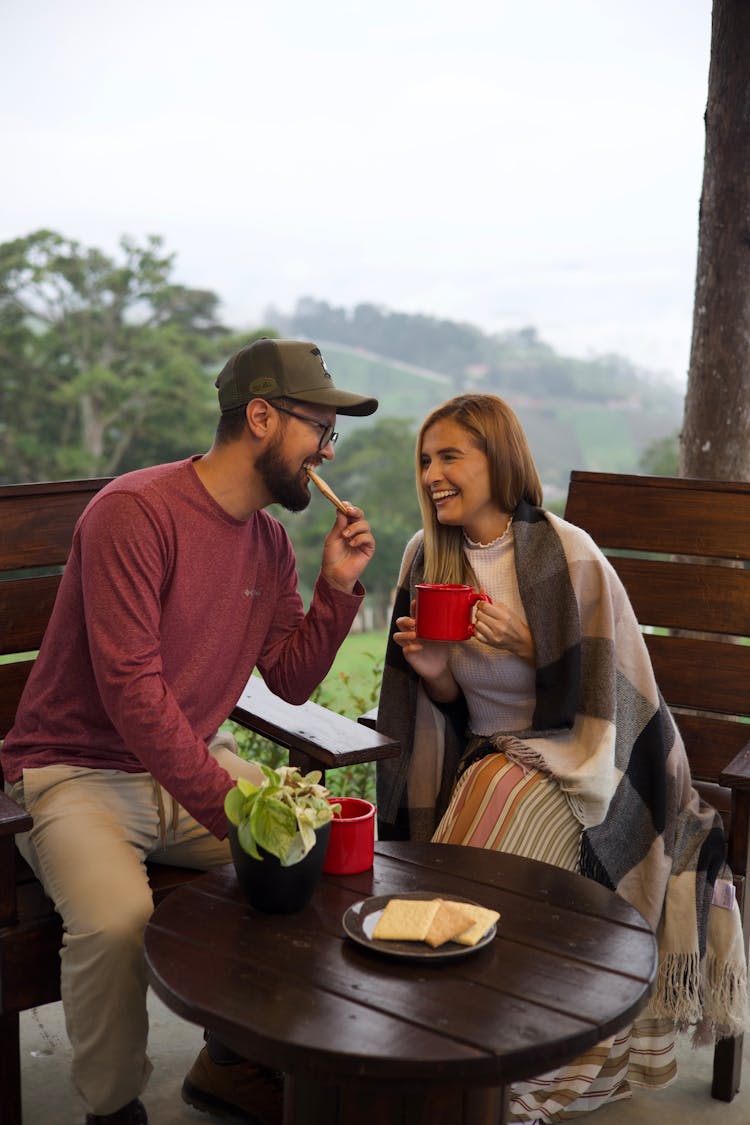 A Couple Sitting On A Porch And Laughing 