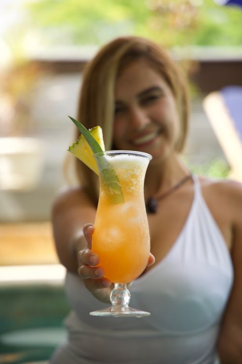 Free Woman holding a tropical cocktail near a pool, with a vibrant summer vibe. Stock Photo