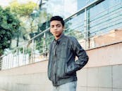 一位穿着夹克的时尚少年在城市背景下自信地在户外摆姿势