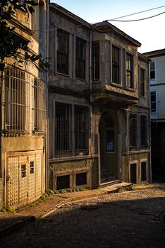 An atmospheric photo of an abandoned building on a sunlit cobblestone street, evoking urban decay.