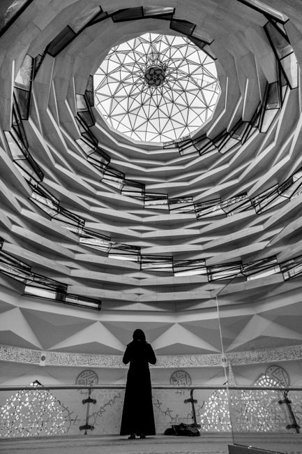 A person in black stands under an ornate dome with a glass ceiling.