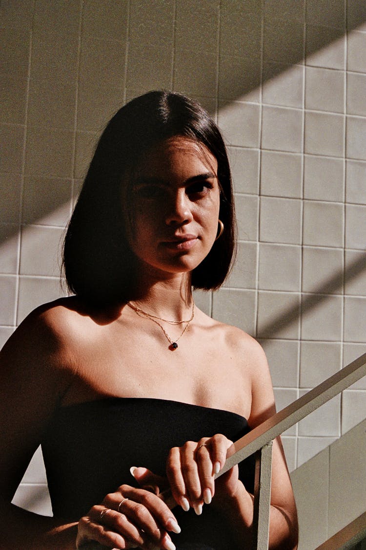 A Woman In A Black Dress Standing On A Stairway