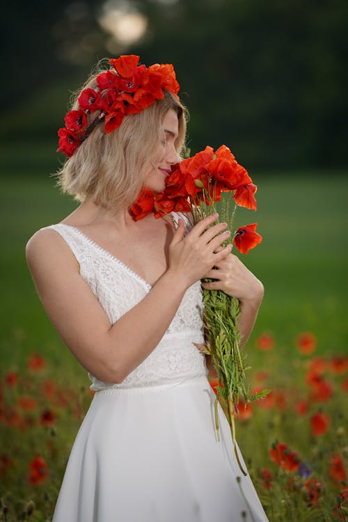 Woman Holding Bouquet of Red Flowers on a Field 