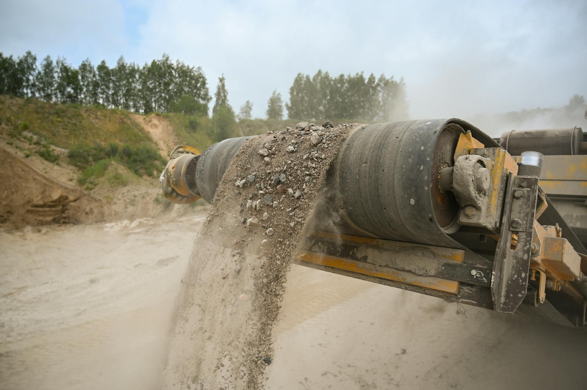 A close-up of an industrial conveyor belt moving gravel at a construction site