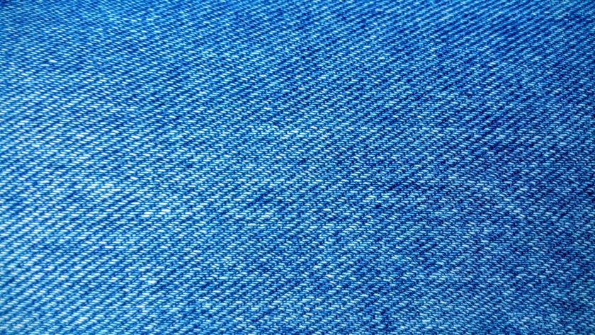 Macro close-up of indigo denim, the diagonal twill line and white weft flecks visible