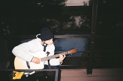 Man Sitting on a Porch and Playing the Guitar 