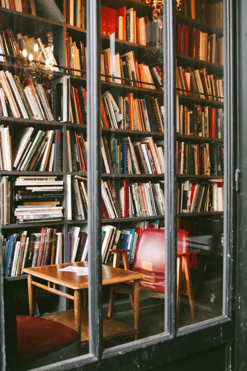 A charming library corner featuring bookshelves filled with books, wooden chairs, and a small table.