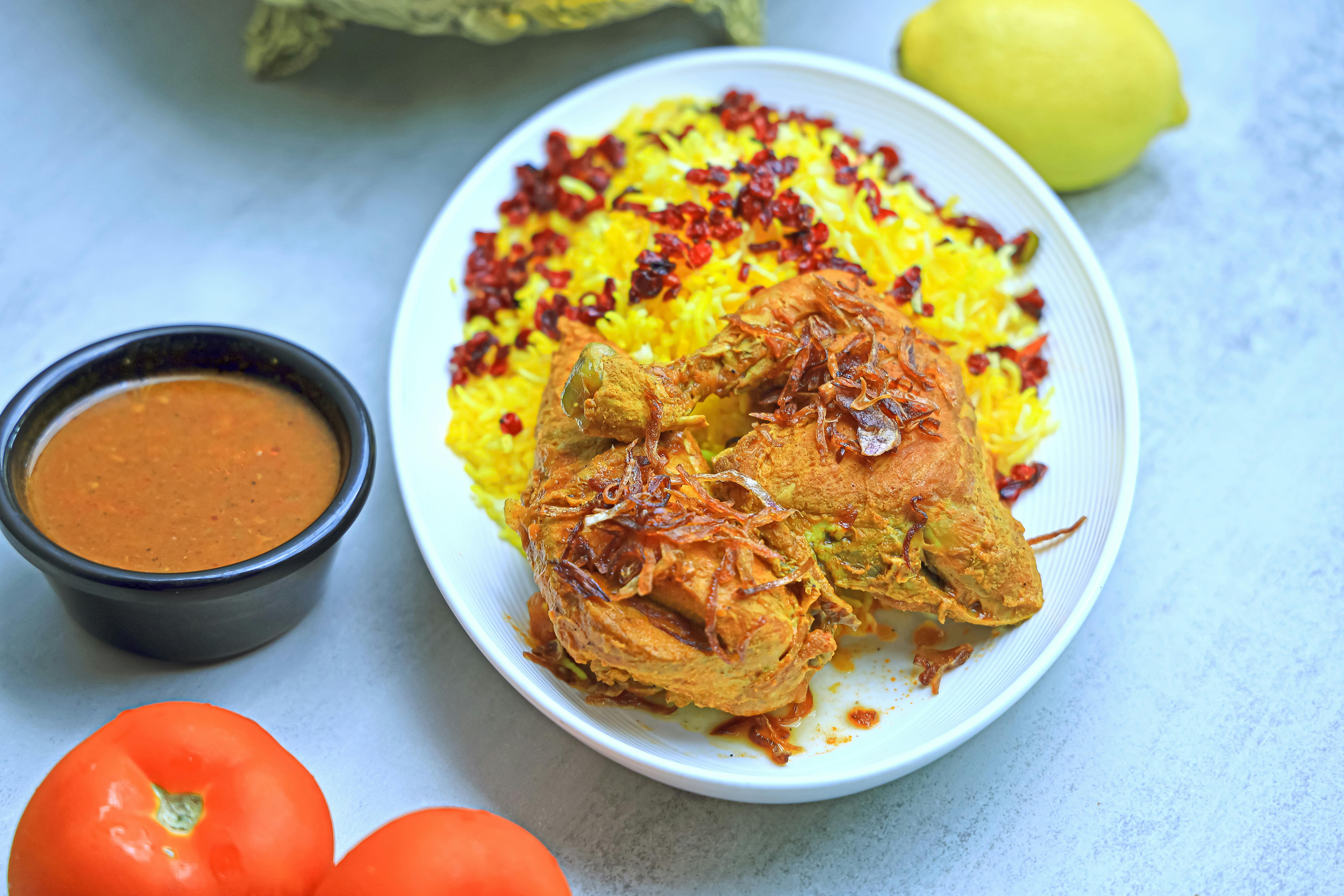 a plate of chicken and rice with tomatoes and sauce