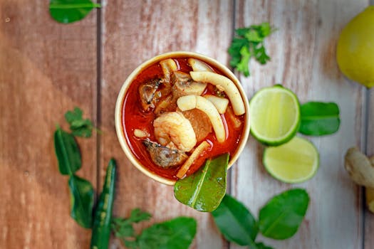 Delicious seafood soup with shrimp, lime, and fresh herbs on a rustic wooden table.