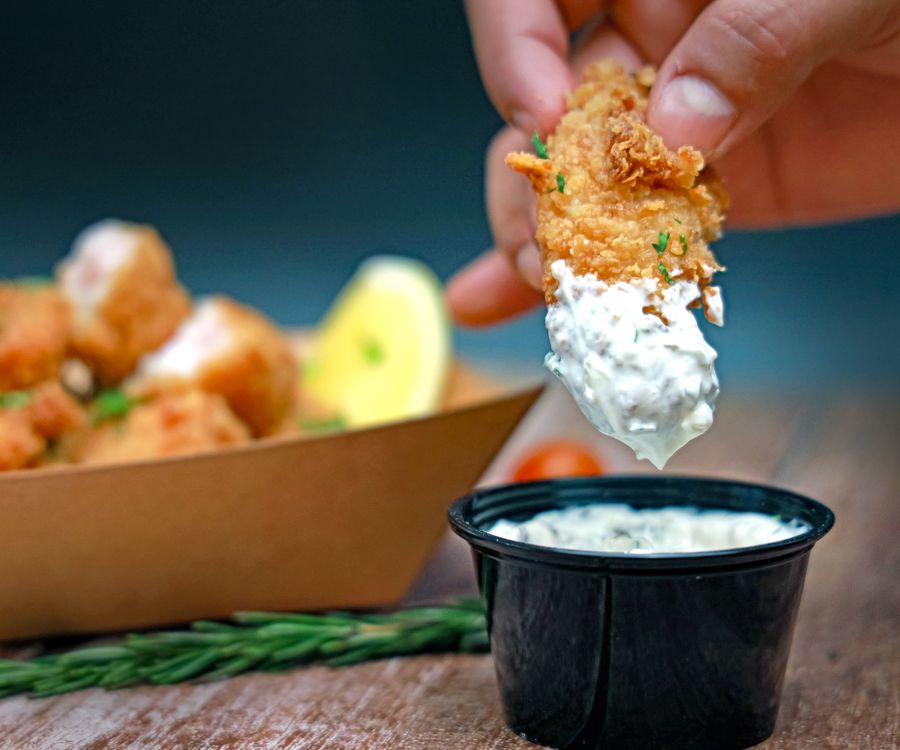 Dip Something In A person dipping a piece of fish into a bowl of dip · Free Stock Photo