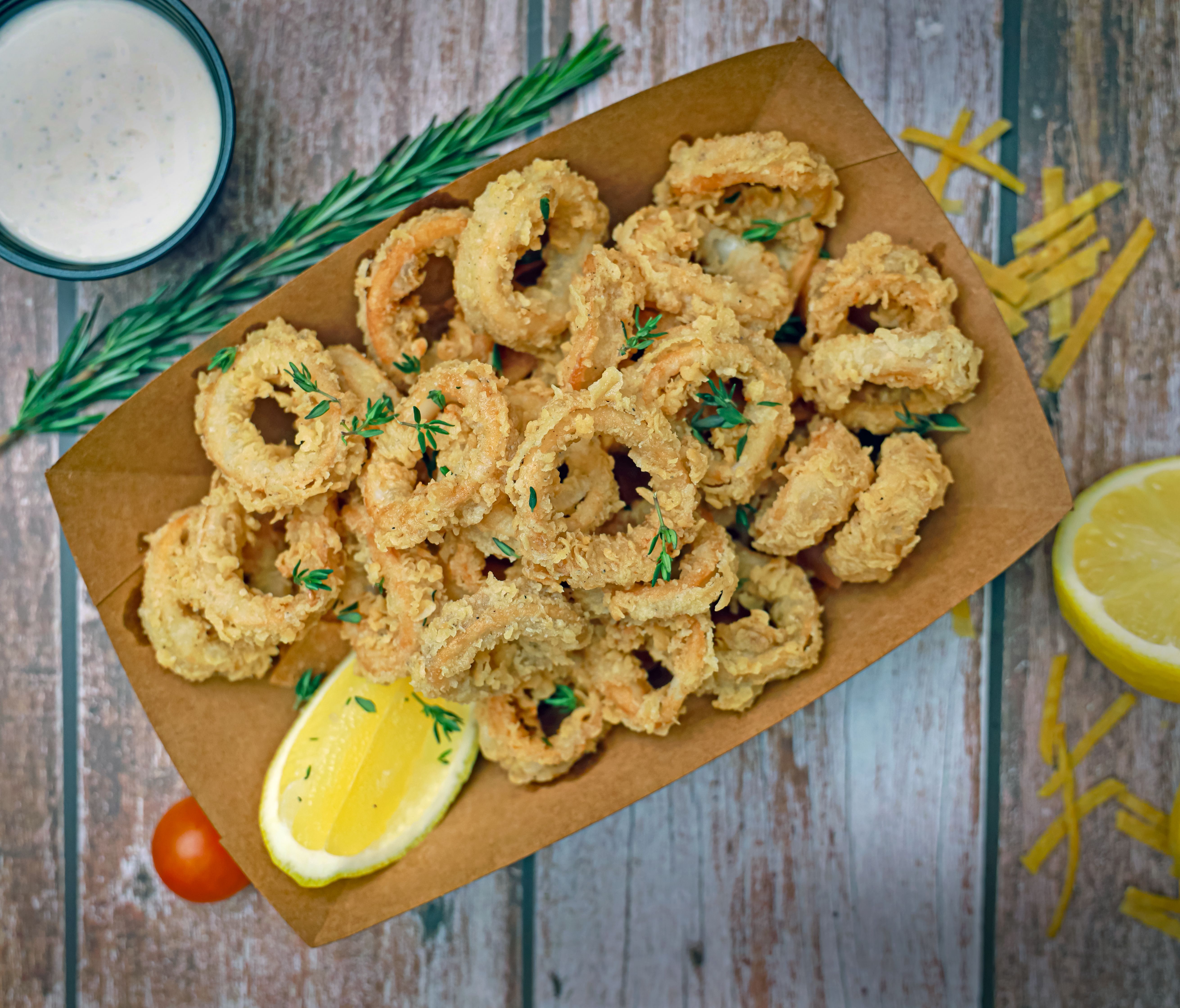 Crispy fried calamari rings served with fresh lemon wedges, ideal for seafood lovers.
