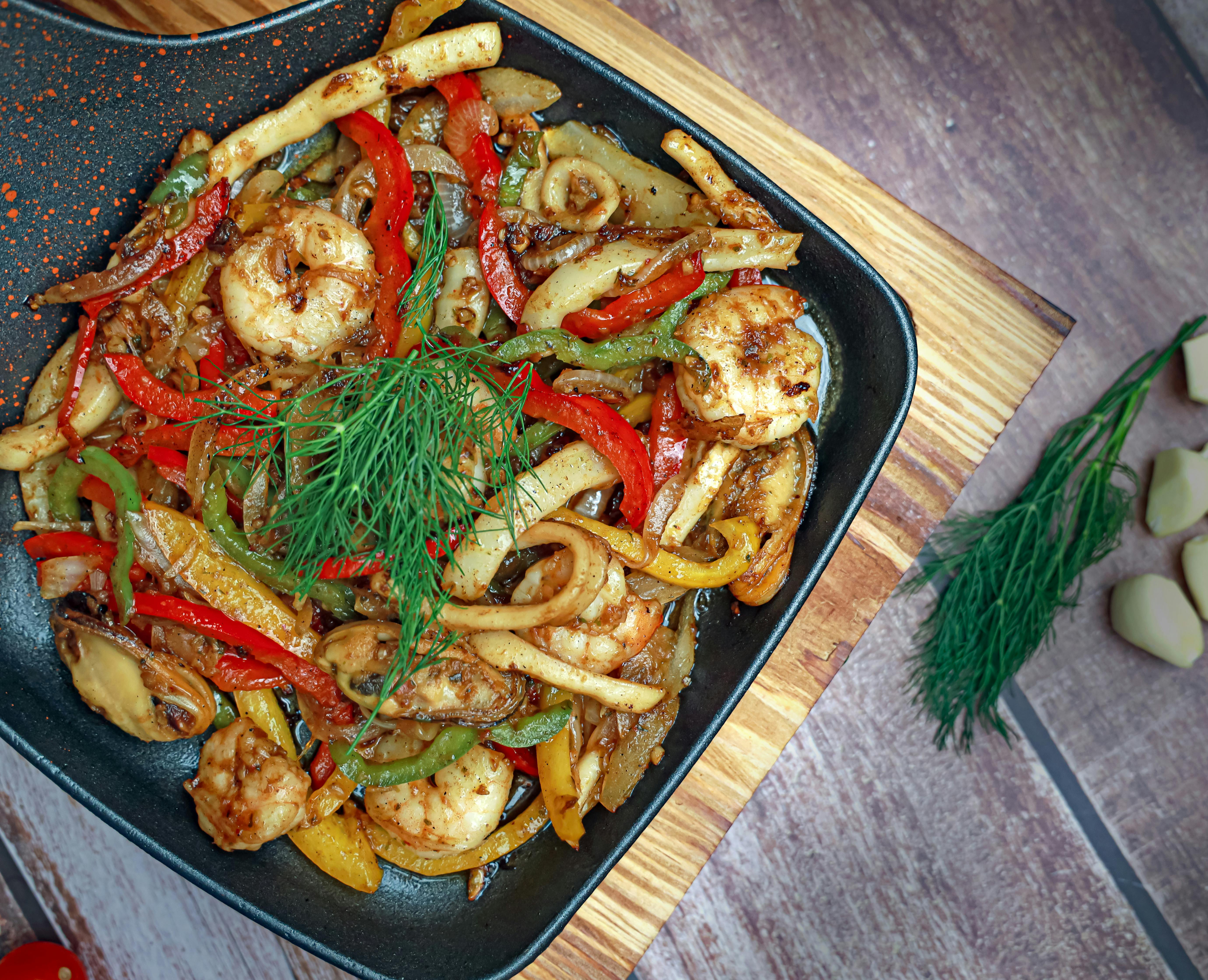 Delicious seafood stir-fry with shrimp, peppers, and herbs in a pan.