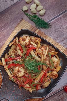 Colorful seafood stir fry with bell peppers and herbs in a skillet.
