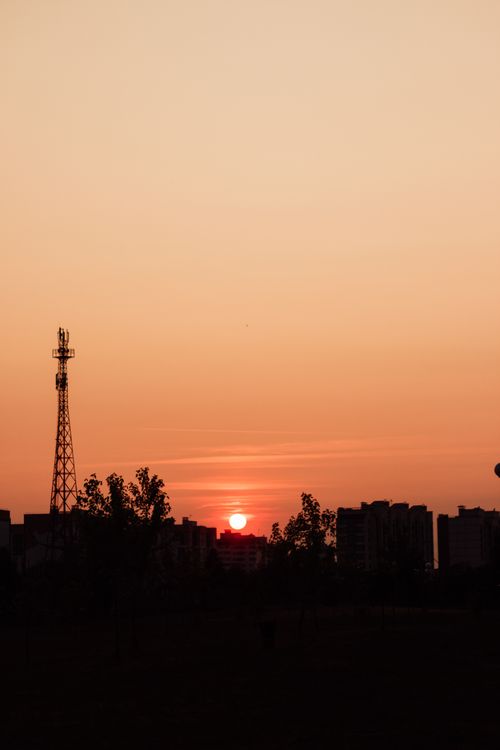 Free Silhouette of urban buildings and a tower against a warm sunset sky. Stock Photo