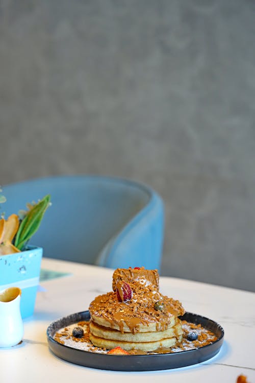 Free A mouthwatering stack of pancakes drizzled with caramel sauce on a table. Stock Photo