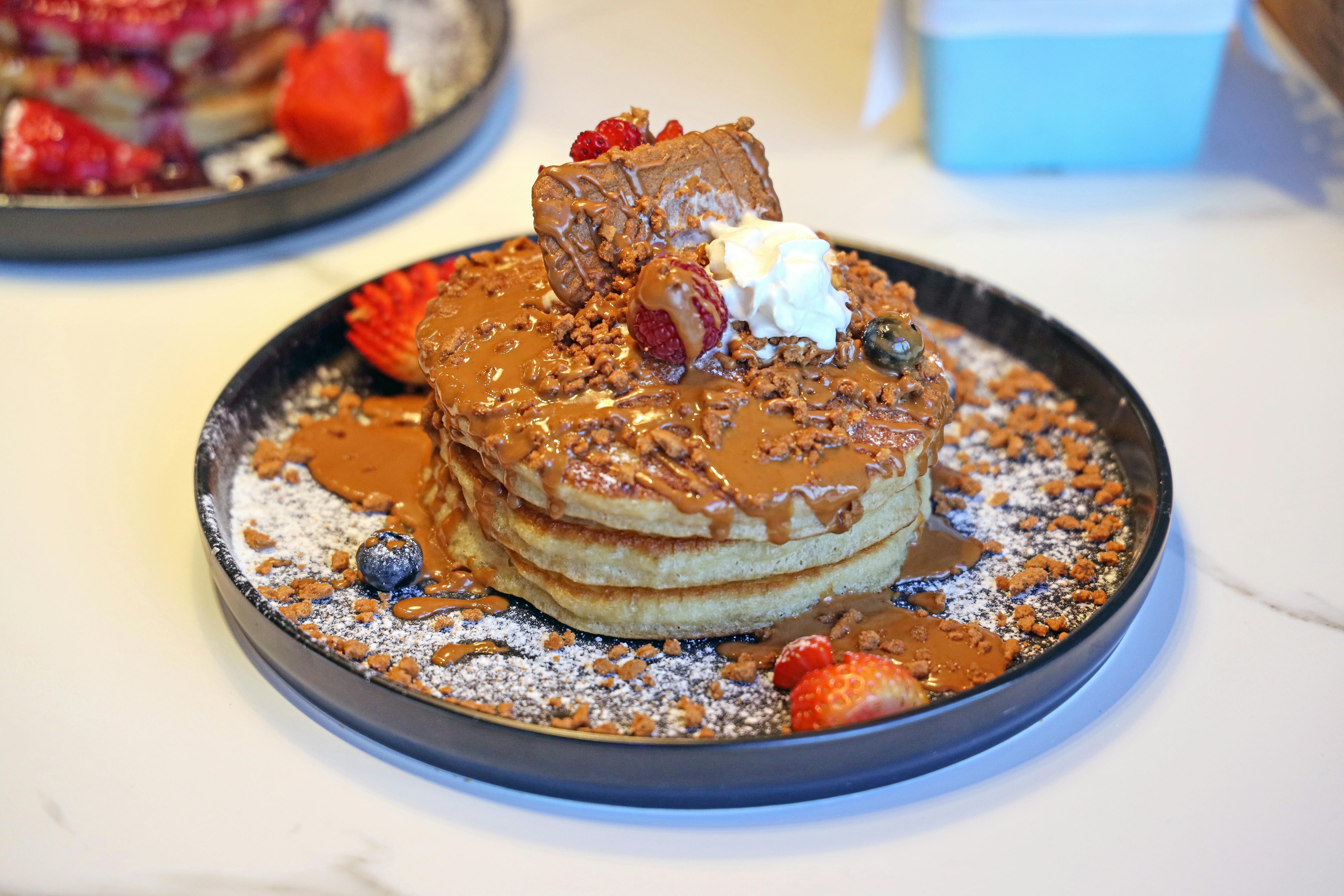 A massive, decadent pancake stack with toppings - Best brunch spots Sunshine Coast