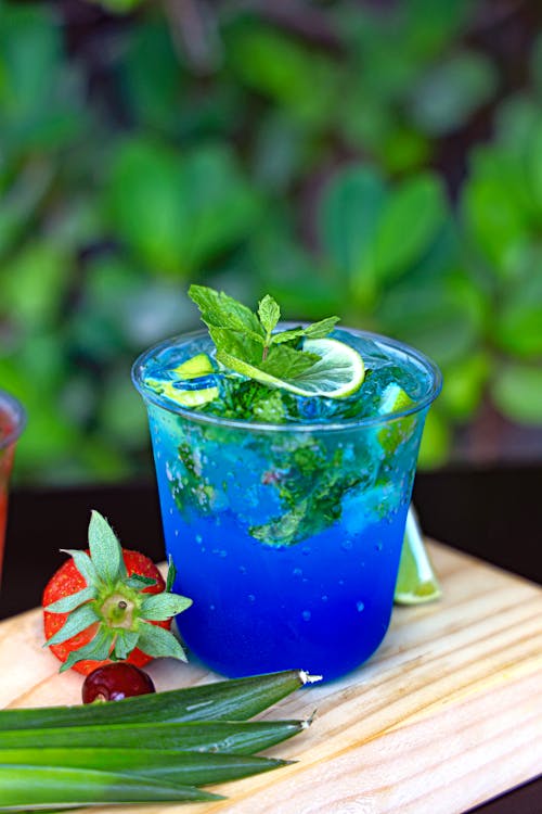 A blue drink with strawberries and mint leaves