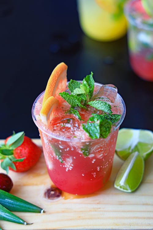 A drink with fruit and lime garnish on a cutting board