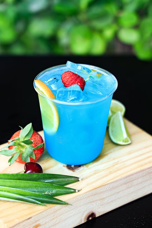 A blue drink with lime, strawberries and a lime wedge