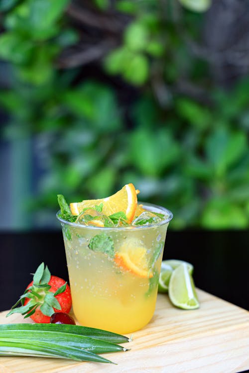 A drink with orange slices and strawberries on a cutting board