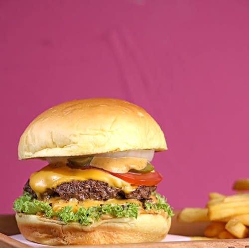 A cheeseburger with cheese, lettuce, tomatoes and fries