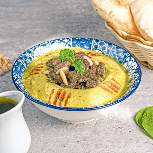 A bowl of soup with meat and bread on a table