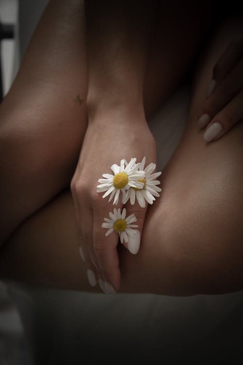Woman Hand with Daisies on Legs