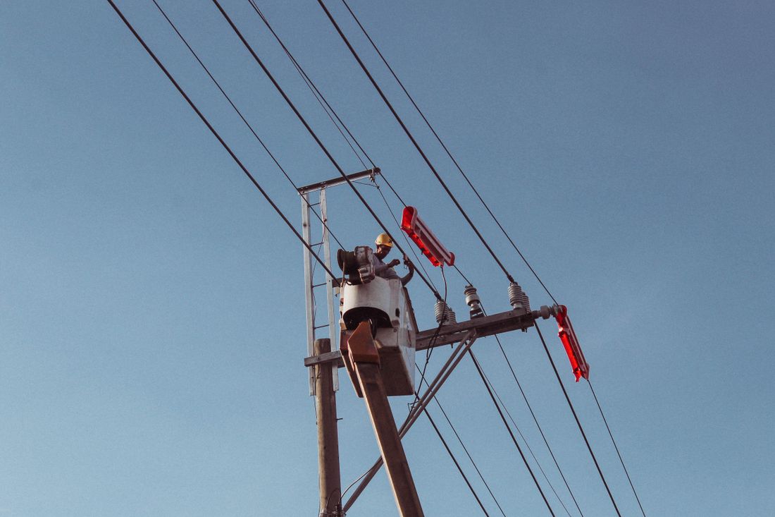 Trabajador en canastilla elevadora reparando una línea eléctrica