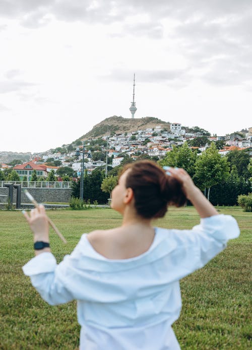 Woman Standing in a Park with the View of a TV Tower on a Hill in Baku, Azerbaijan