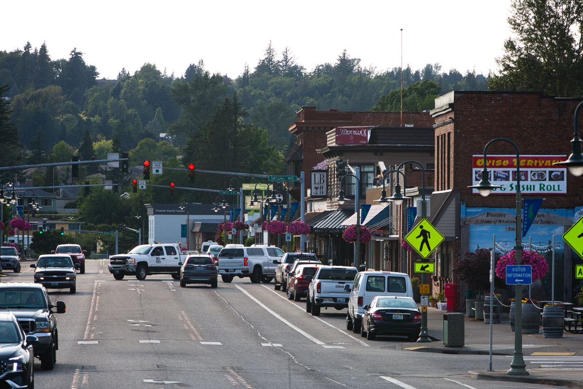 Lively urban street with shops, cars and pedestrians