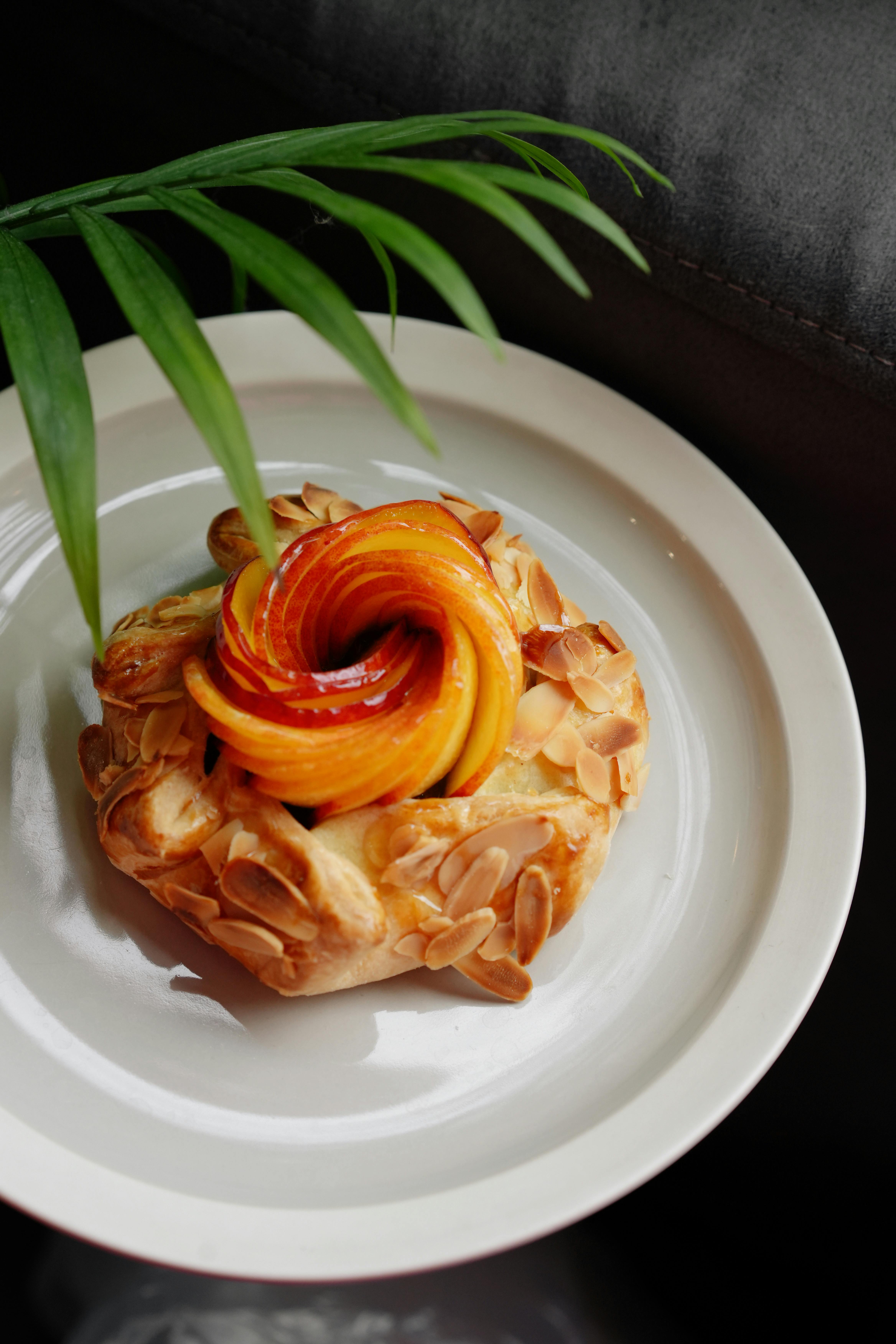 Delicious almond tart topped with glazed fruit elegantly presented on a plate.