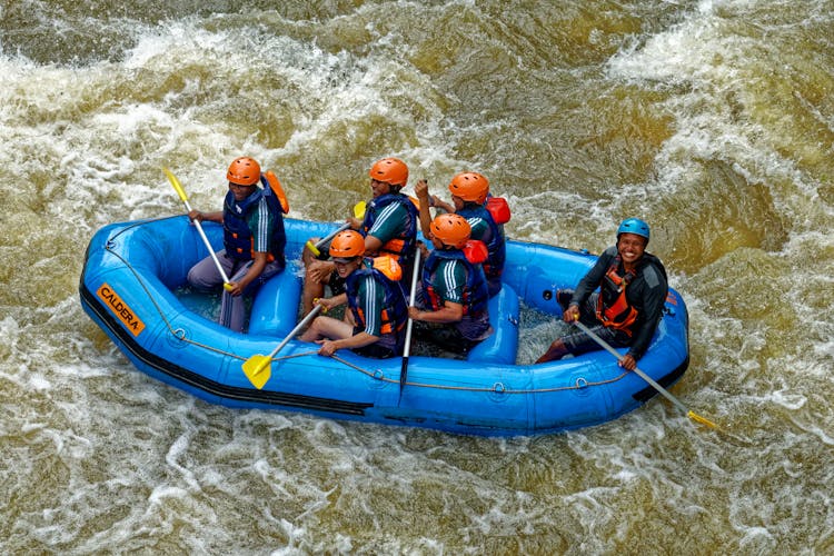 Group Of People Riding Blue Raft On Body Of Water