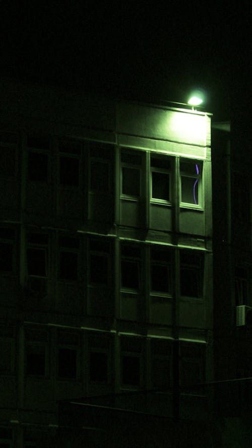 Green Light on Apartment Building in City at Night
