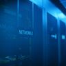 A row of modern server racks illuminated by blue light in a dark data center.