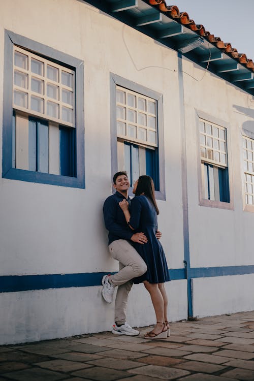 A Couple Standing next to a Building, Hugging and Smiling 