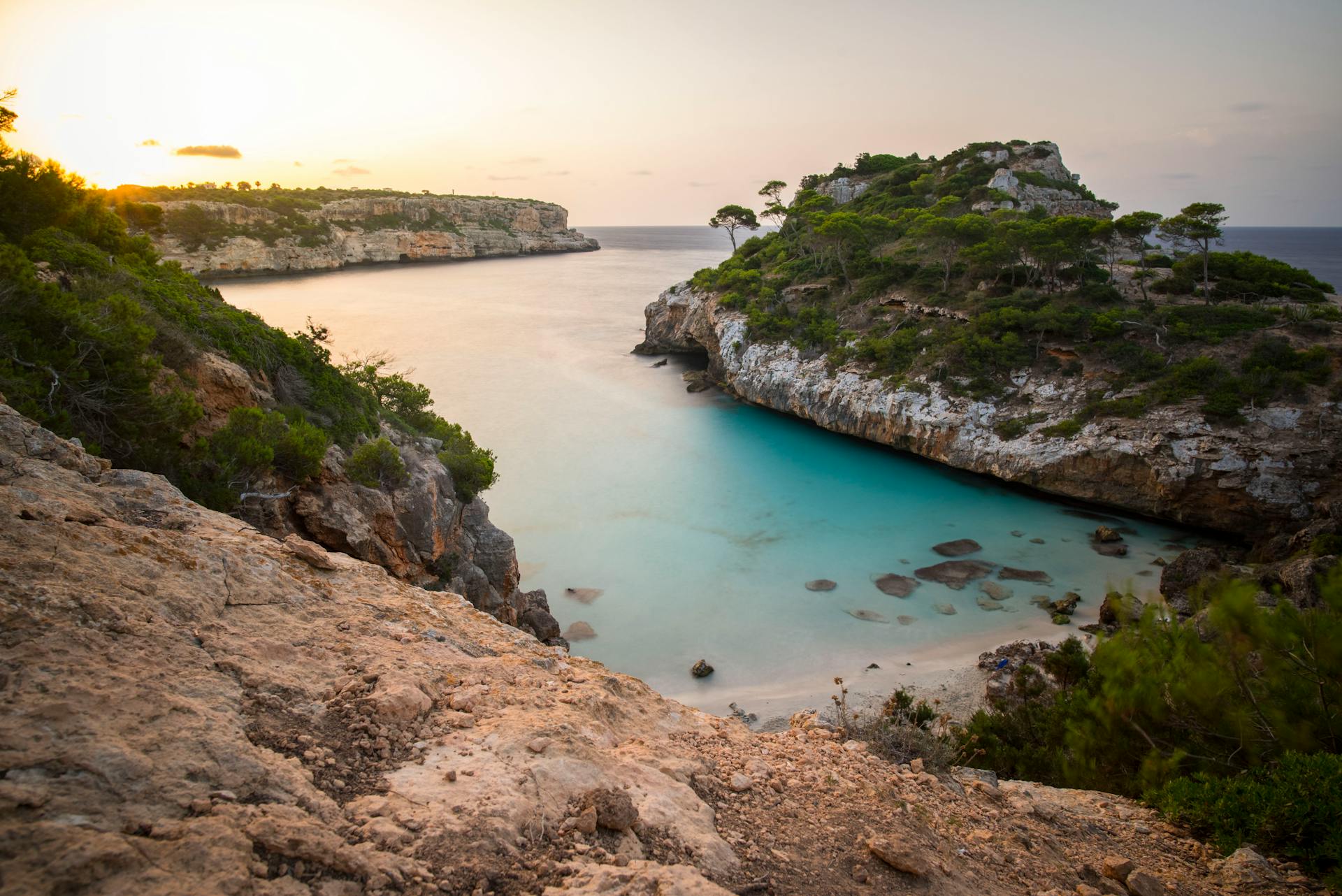 Idyllic cove at sunset with turquoise waters and rocky cliffs, perfect for a tropical escape.