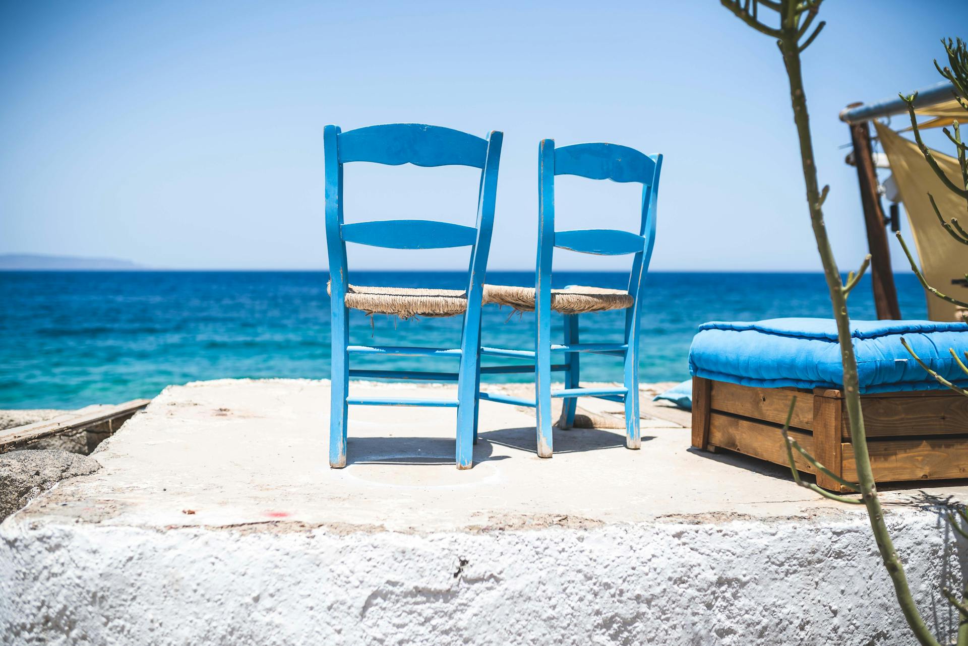 Two blue chairs on a terrace by the sea, perfect for a relaxing tropical vacation.