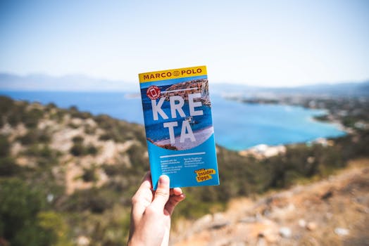 一个人拿着旅行指南，在明亮的蓝天下俯瞰风景优美的海岸线