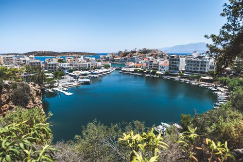 Free Picturesque harbor in Agios Nikolaos, Crete surrounded by urban architecture and clear blue waters. Stock Photo