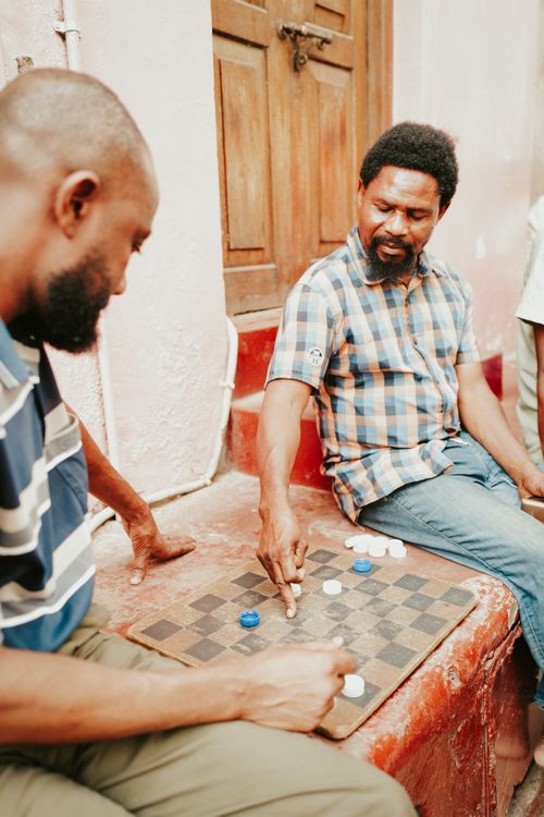 Free Two men engage in a game of checkers outside in Sansibar, Tanzania. Stock Photo