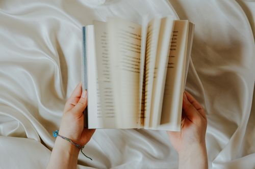 Free Hands flipping through a book on a silky fabric, captured from above. Stock Photo
