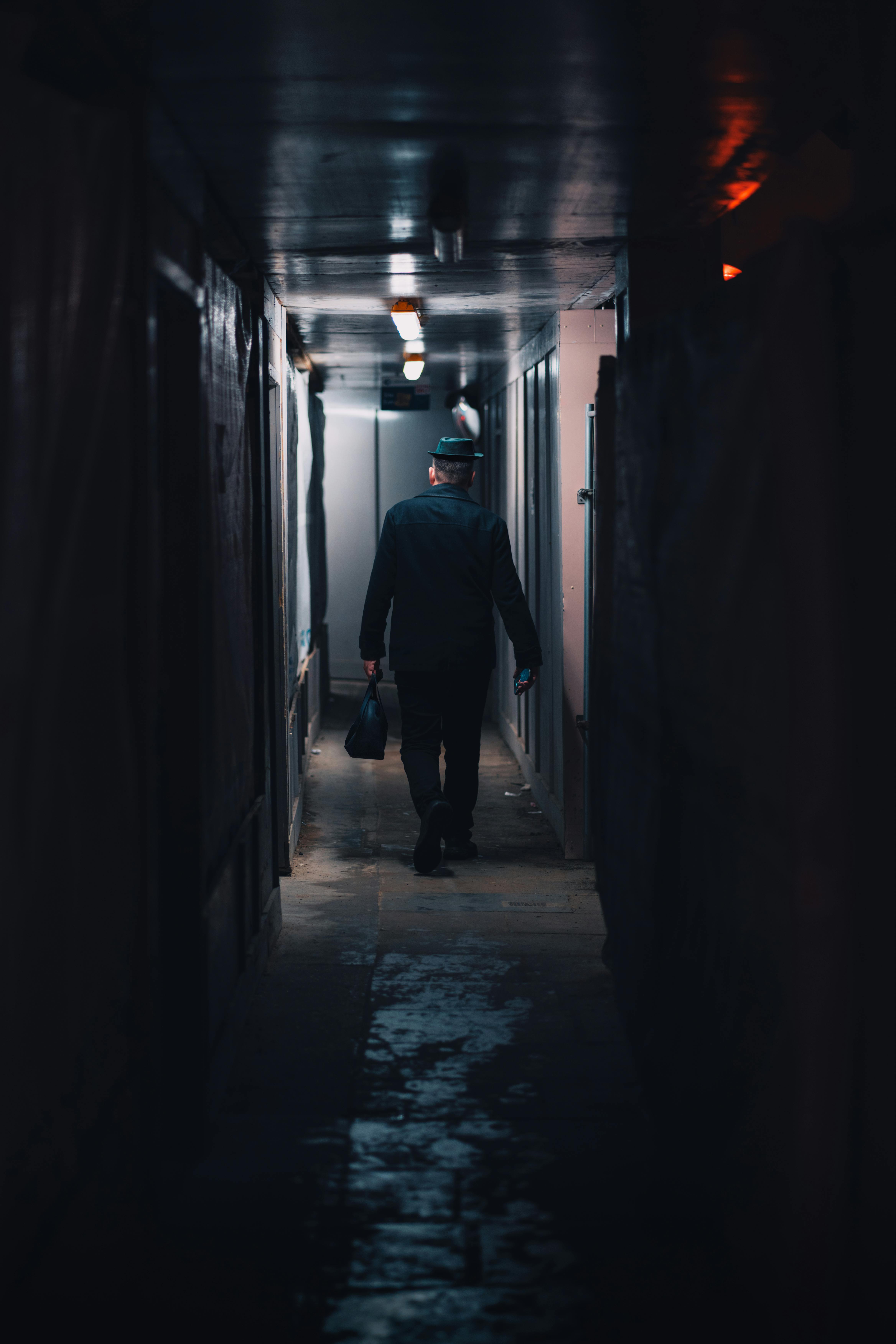 A lone man in a hallway with deep shadows, exuding mystery and elegance.