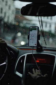 View of a car interior focusing on GPS navigation with raindrops on windshield.