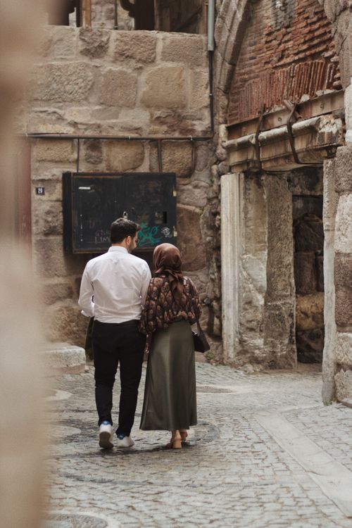 Free A couple strolls together through an ancient stone street, evoking a sense of history and culture. Stock Photo