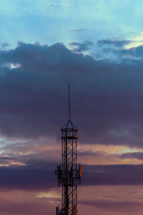 Free A lone radio mast silhouette against a dramatic, dusk sky with layered rain clouds. Stock Photo