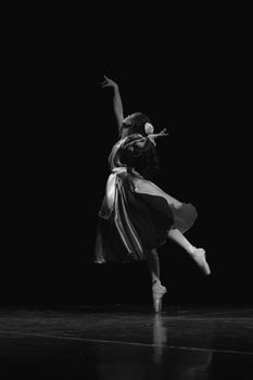 Elegant ballerina performs on stage in a stunning black and white shot.