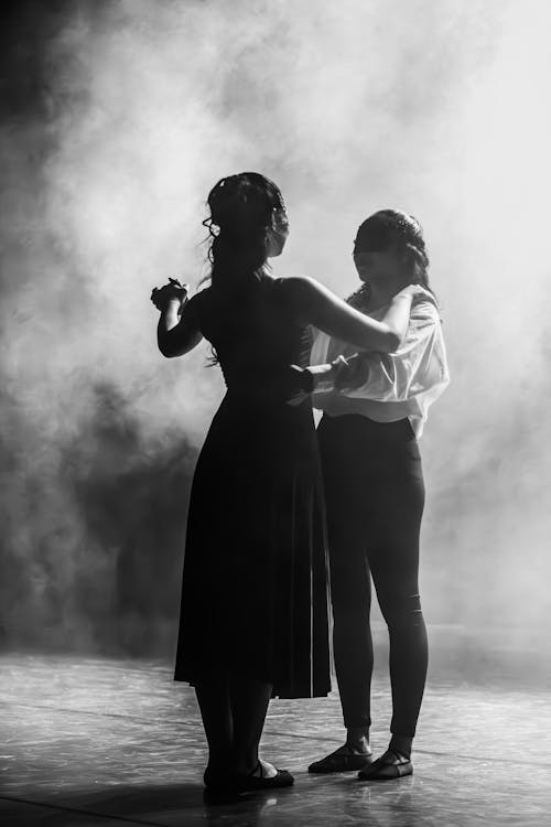 Black and White Photo of Women Dancing on a Stage in the Smoke