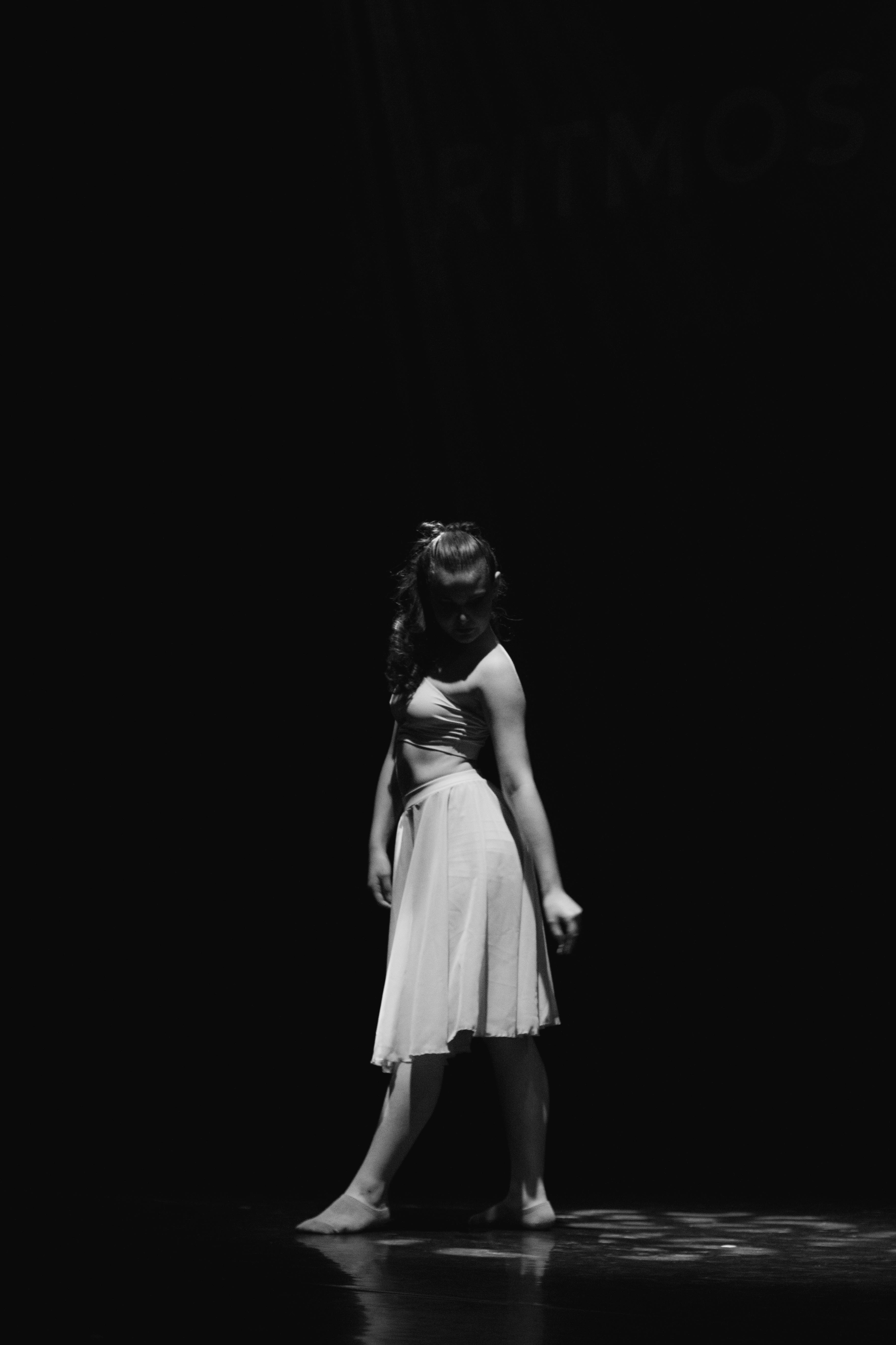 Free Artistic black and white photo of a woman in a dramatic dance pose on stage. Stock Photo