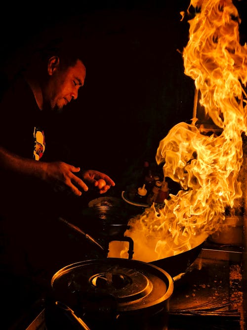 Flame near Man Cooking in Darkness