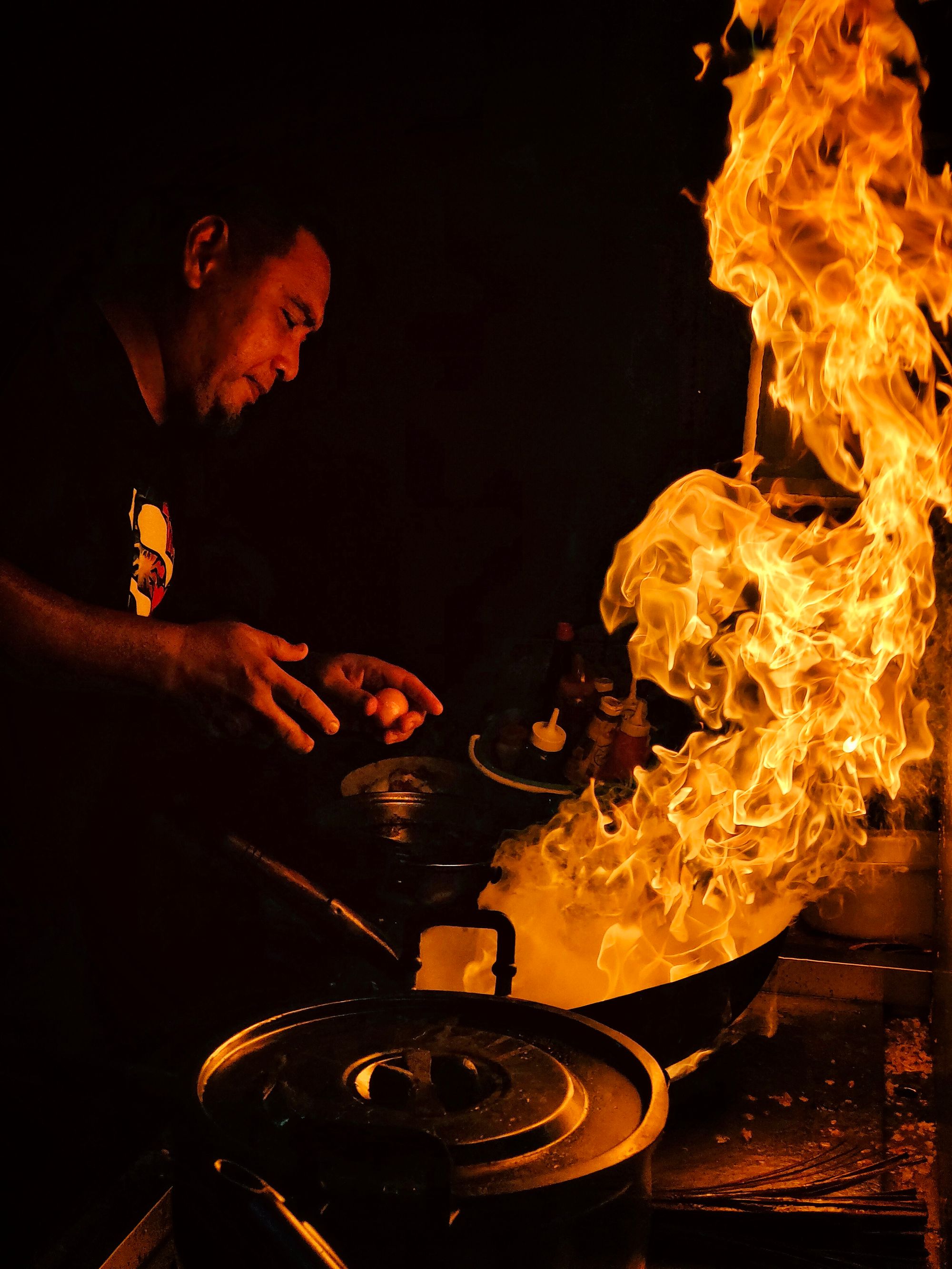 Uno chef governa una grande fiamma nella cucina buia